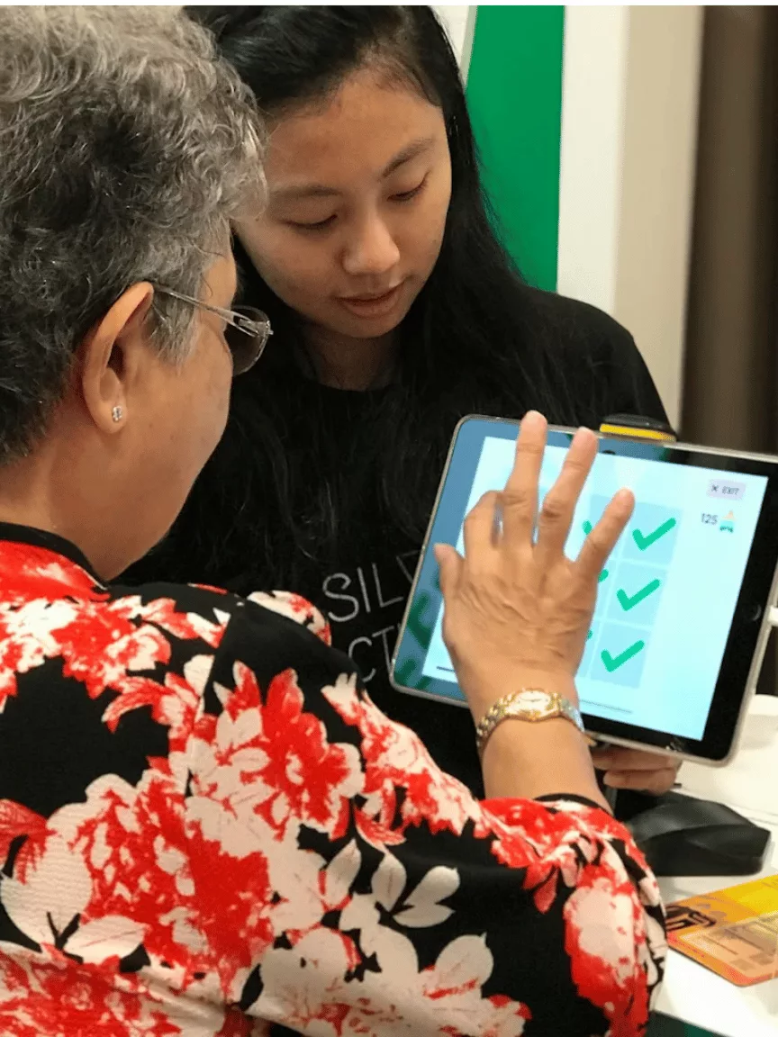 A caregiver and older adult playing together on a tablet