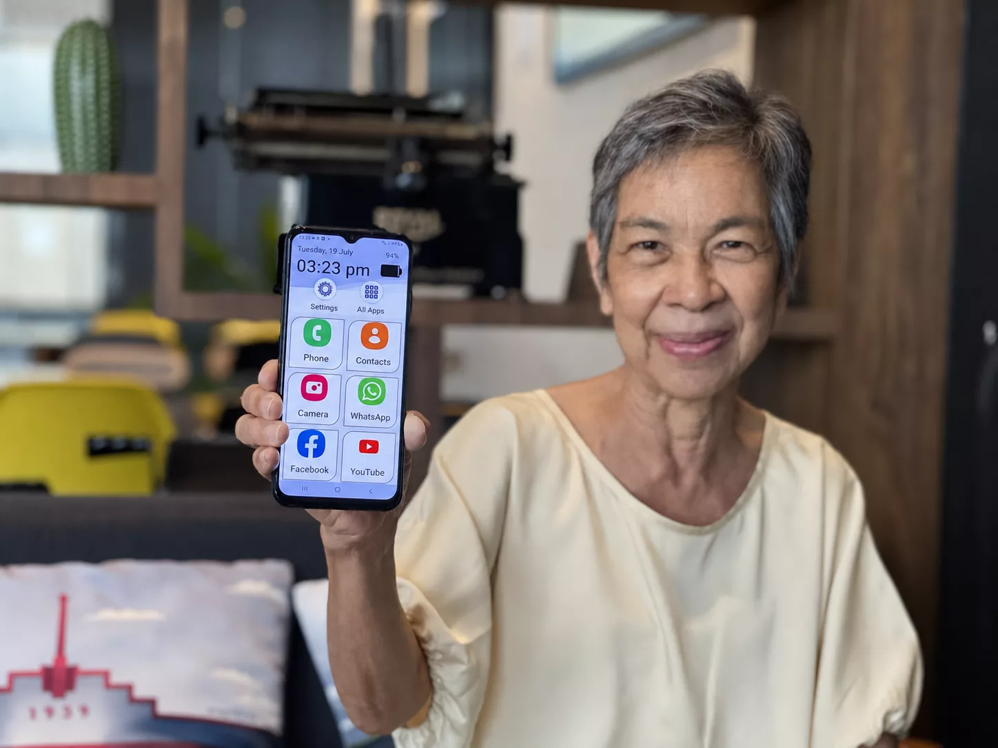 A senior holding a phone showing the ONY Phone home screen